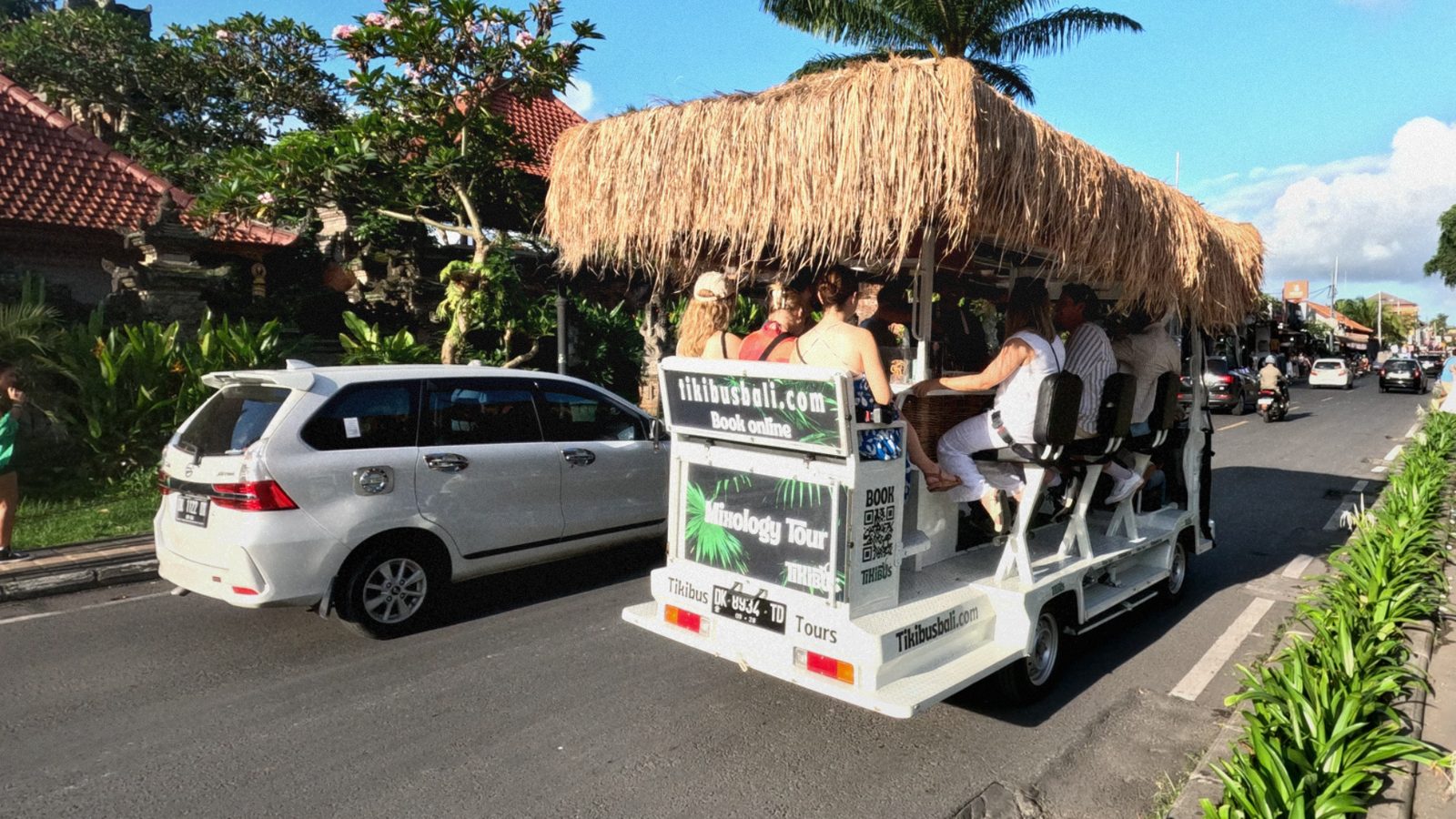 The open-air Tikibus with guests around the bar counter, rolling along a street in Berawa, Canggu